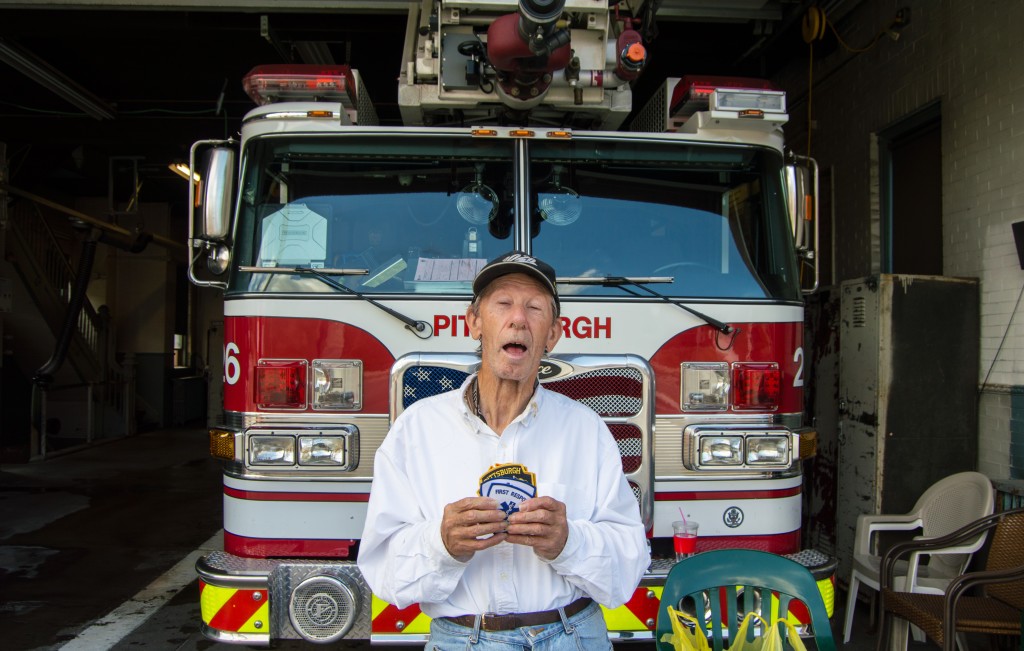 George shows off his numerous patches in front of one of Brookline’s fire trucks at the firehouse. Photo by Joseph Guzy. 