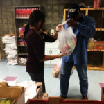 Volunteer Divya Patel, a pharmacy student at the University of Pittsburgh, hands bags of fresh produce to local patron Wayne Young.